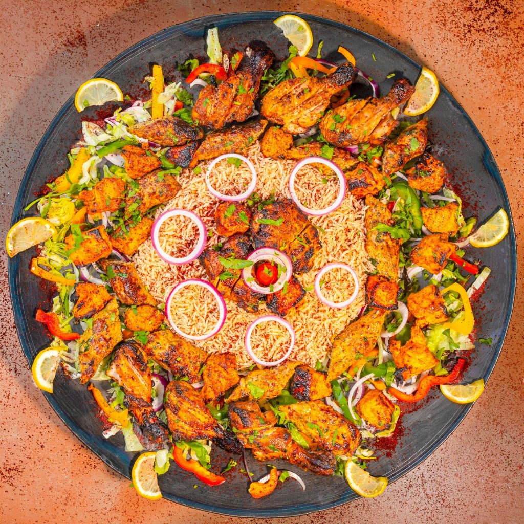 Bawarchi chicken biryani with leg piece, fried chicken, onions, and lemon slices