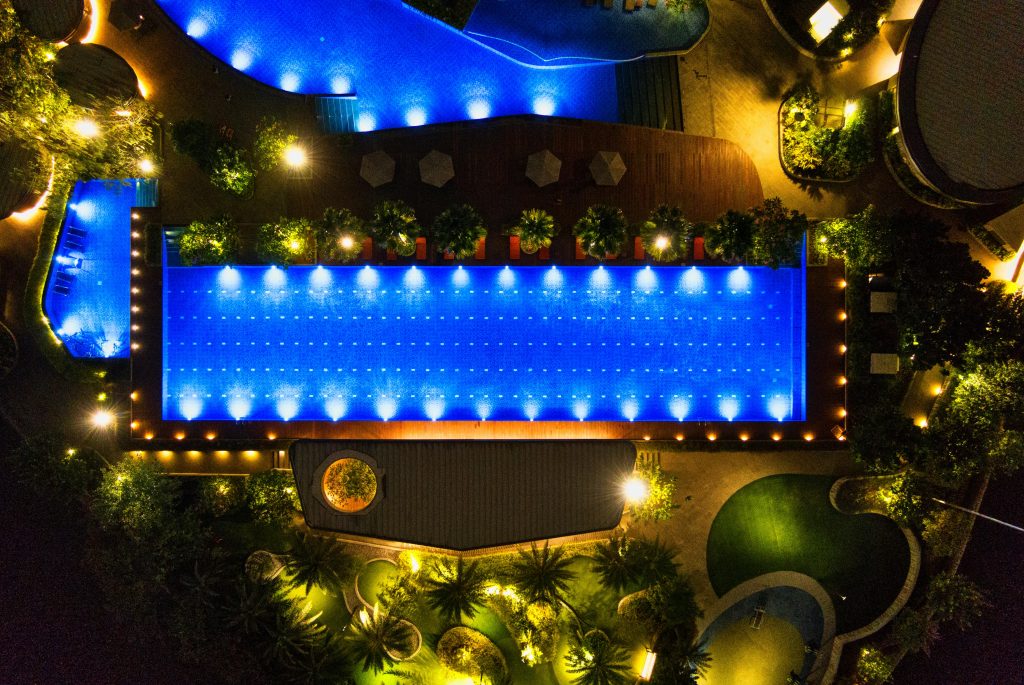 Stunning drone shot of a resort's neon-lit pool in Banten, Hyderabad , showcasing nighttime elegance